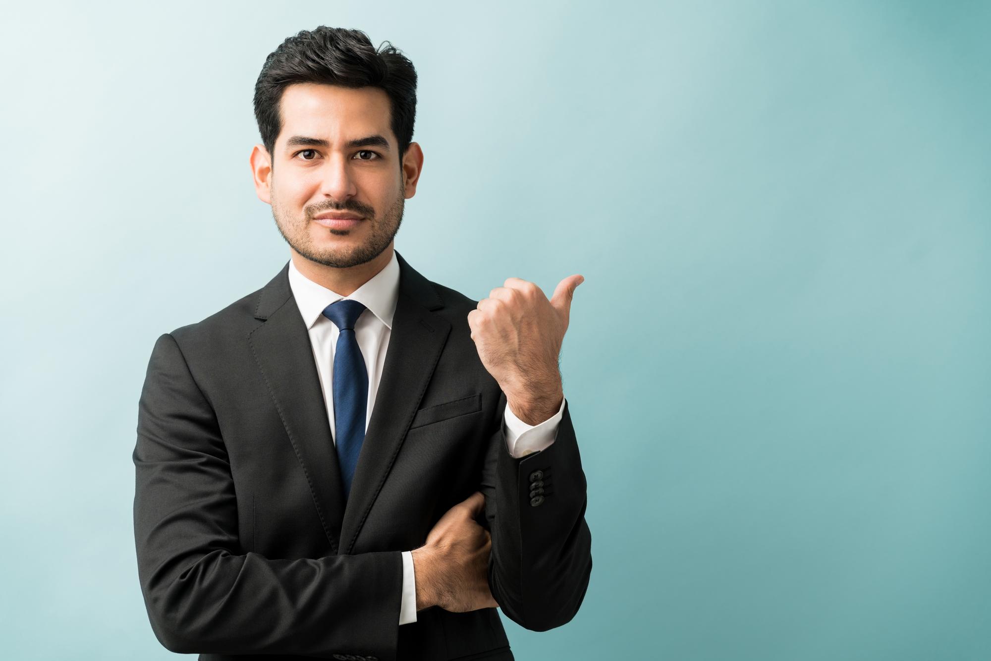 Hispanic Male Executive Gesturing Copy Space While Making Eye Contact Studio